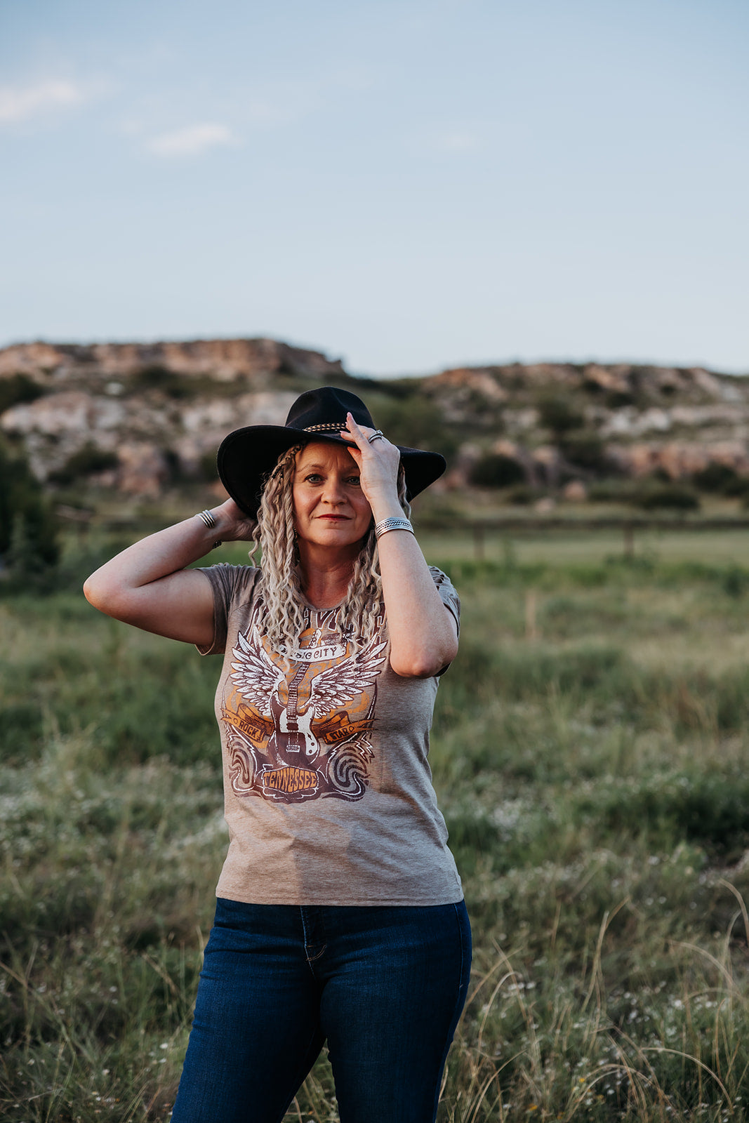 woman in her 50's wearing braid in dreadlock extensions while wearing a western outfit and cowgirl hat