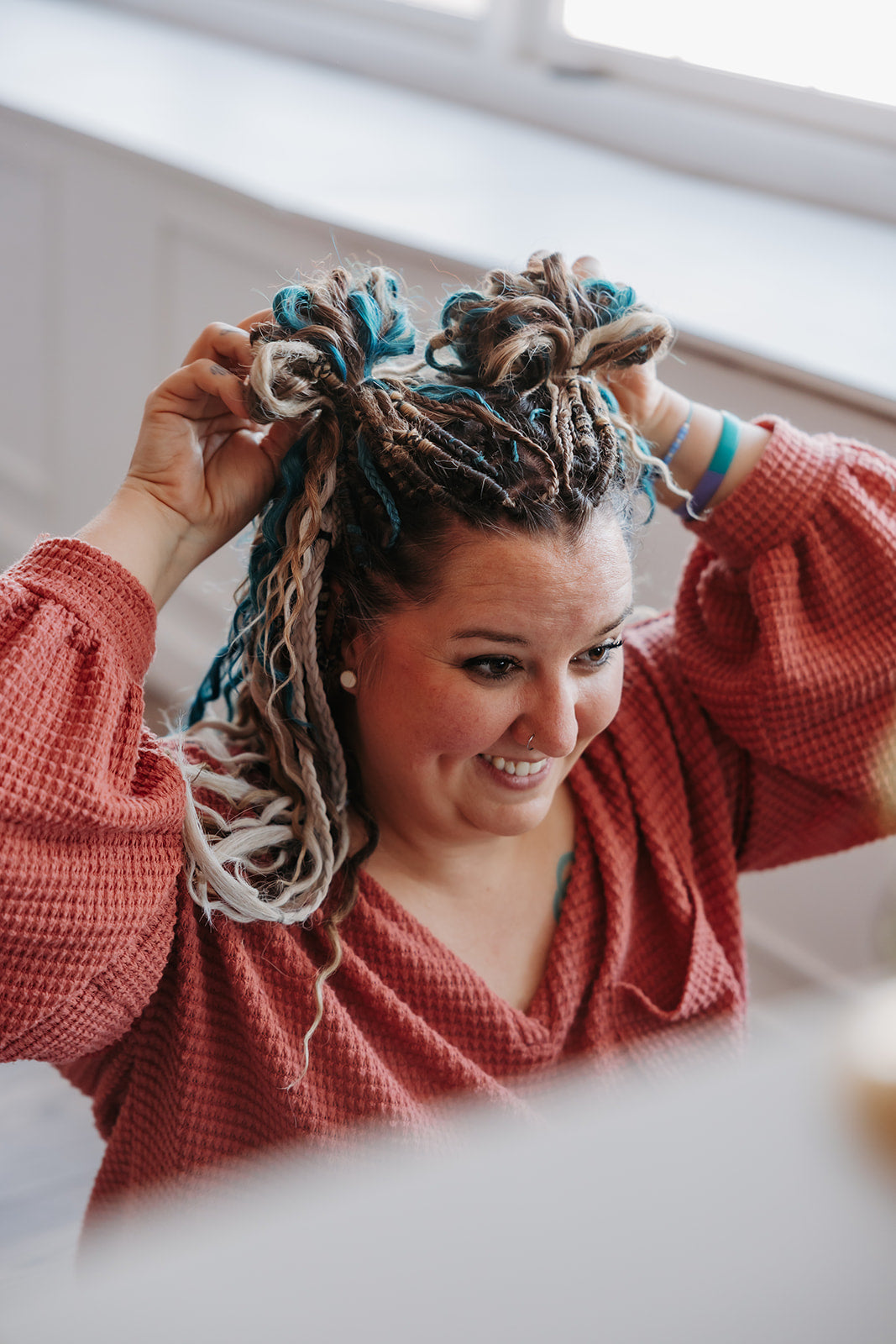 Woman wearing teal, light brown, and blonde Dreadlock extensions with fun buns in