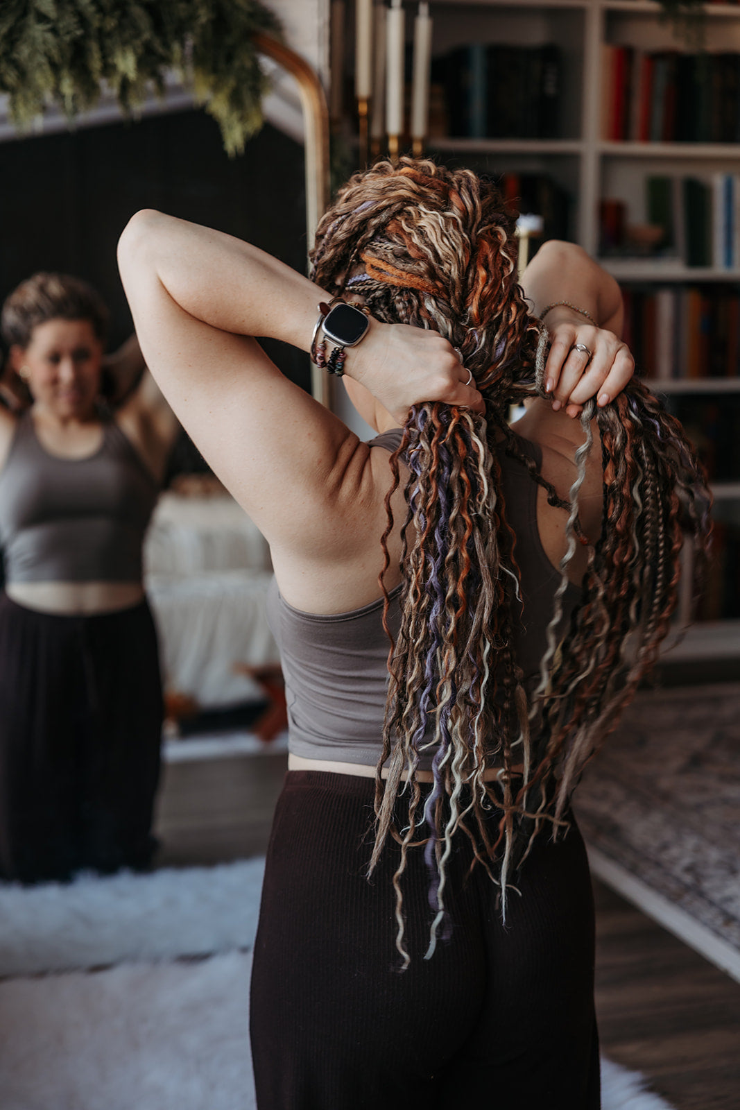 “Woman creating a French braid hairstyle with long hair, ideal for spring hairstyles using braid-in dreadlocks or double ended extensions.”