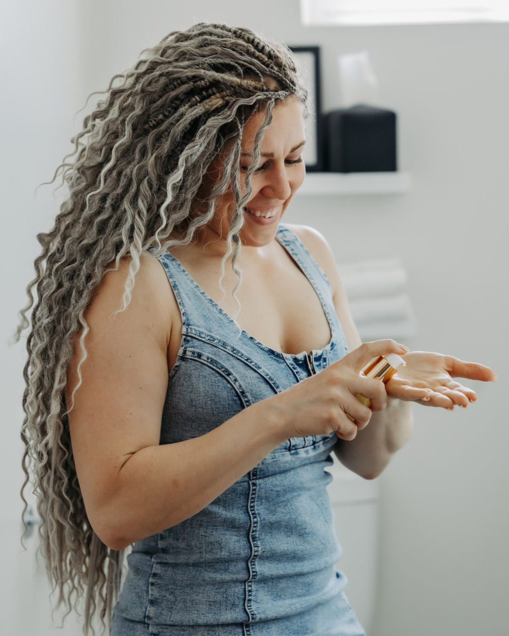 Woman with Venus Long Wavy braid-in hair extensions in Smokey Amber color wearing a denim dress, pumping oil
