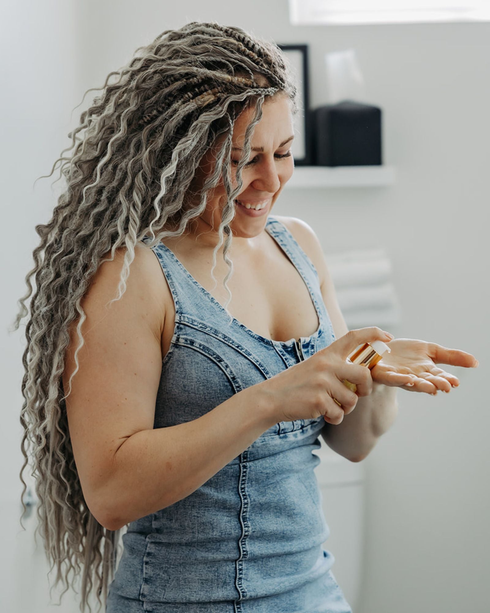 Woman with Venus Long Wavy braid-in hair extensions in Smokey Amber color wearing a denim dress, pumping oil