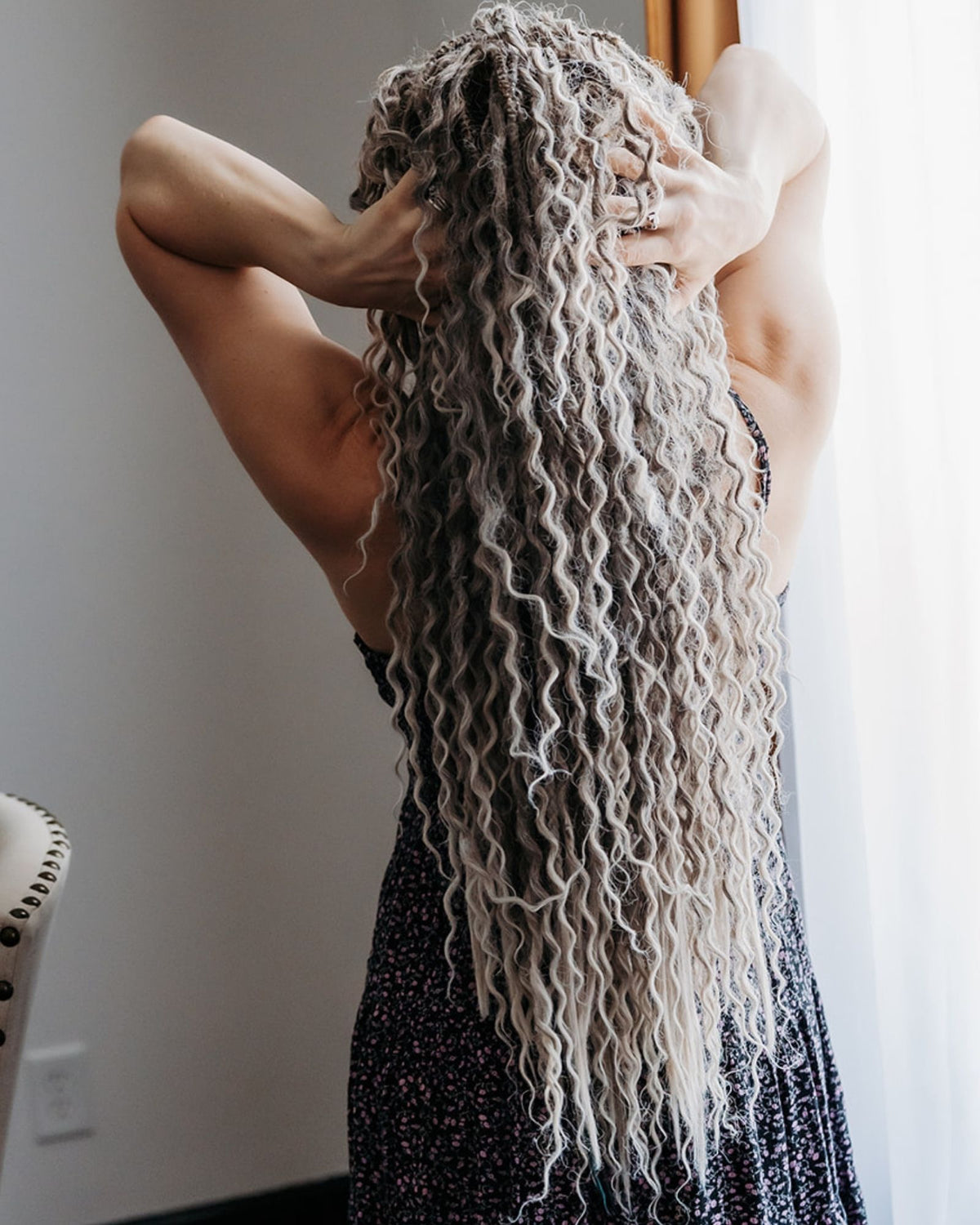 Person with Venus Long Wavy braid-in hair extensions in Smokey Amber color standing in a room with a neutral background