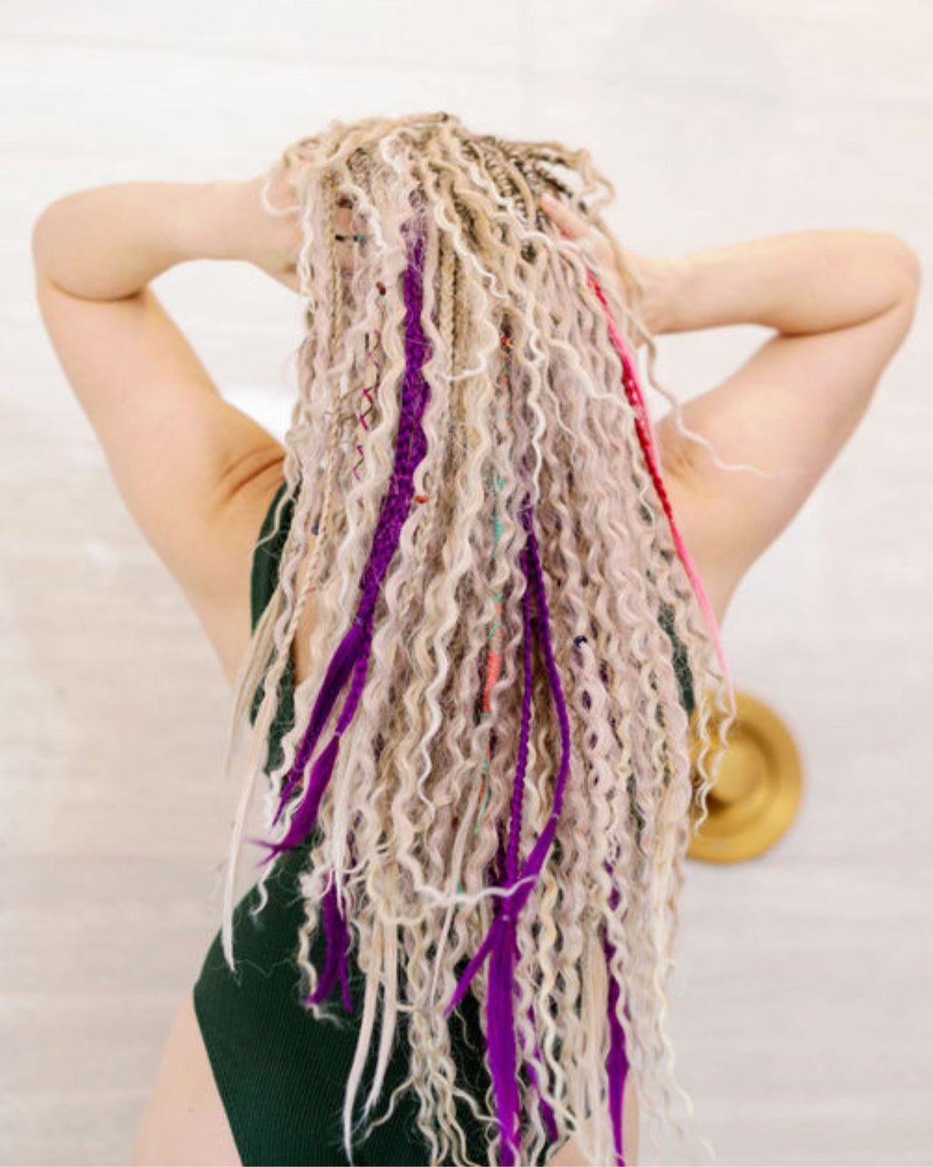 Person with colorful braided hair extensions on a plain background