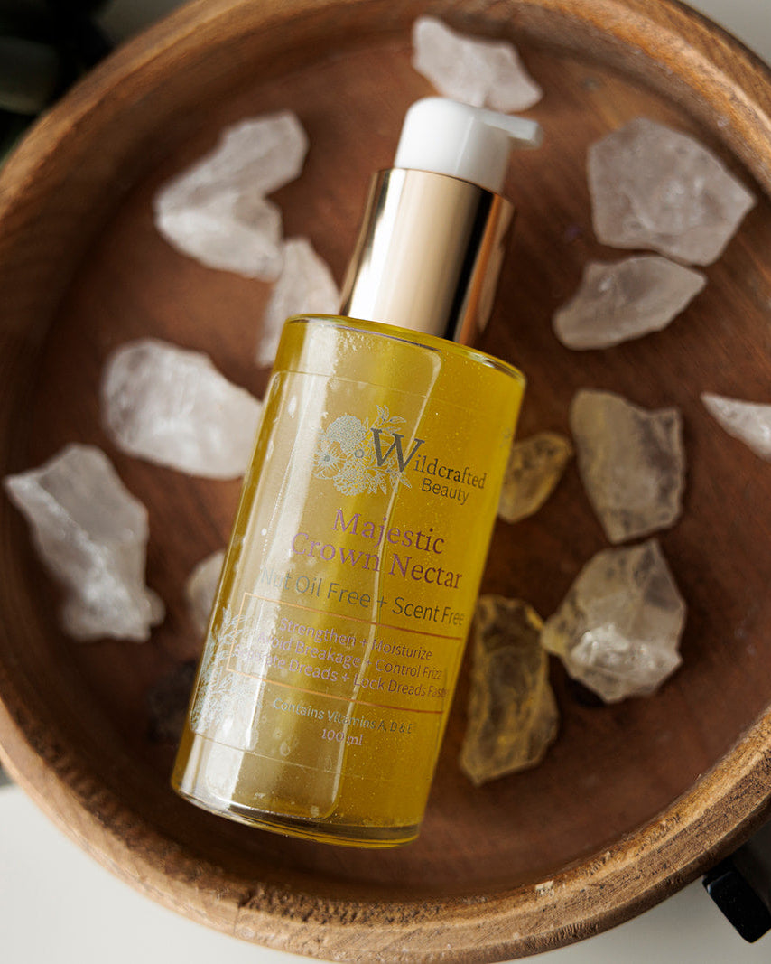 A bottle of Majestic Crown Nectar in a wooden bowl surrounded by quartz crystals.