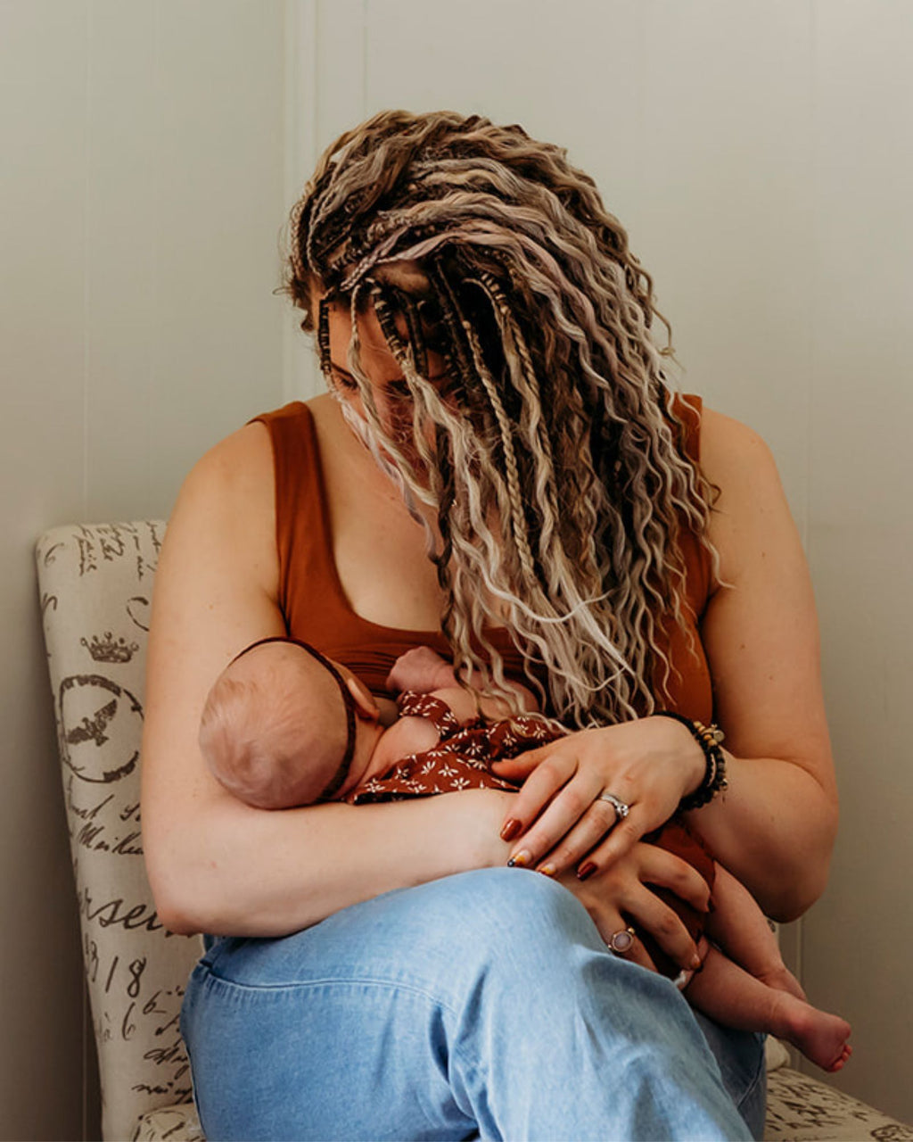 Woman wearing SHORTIES™ Braid-in Hair Extensions breastfeeding a baby in a home setting