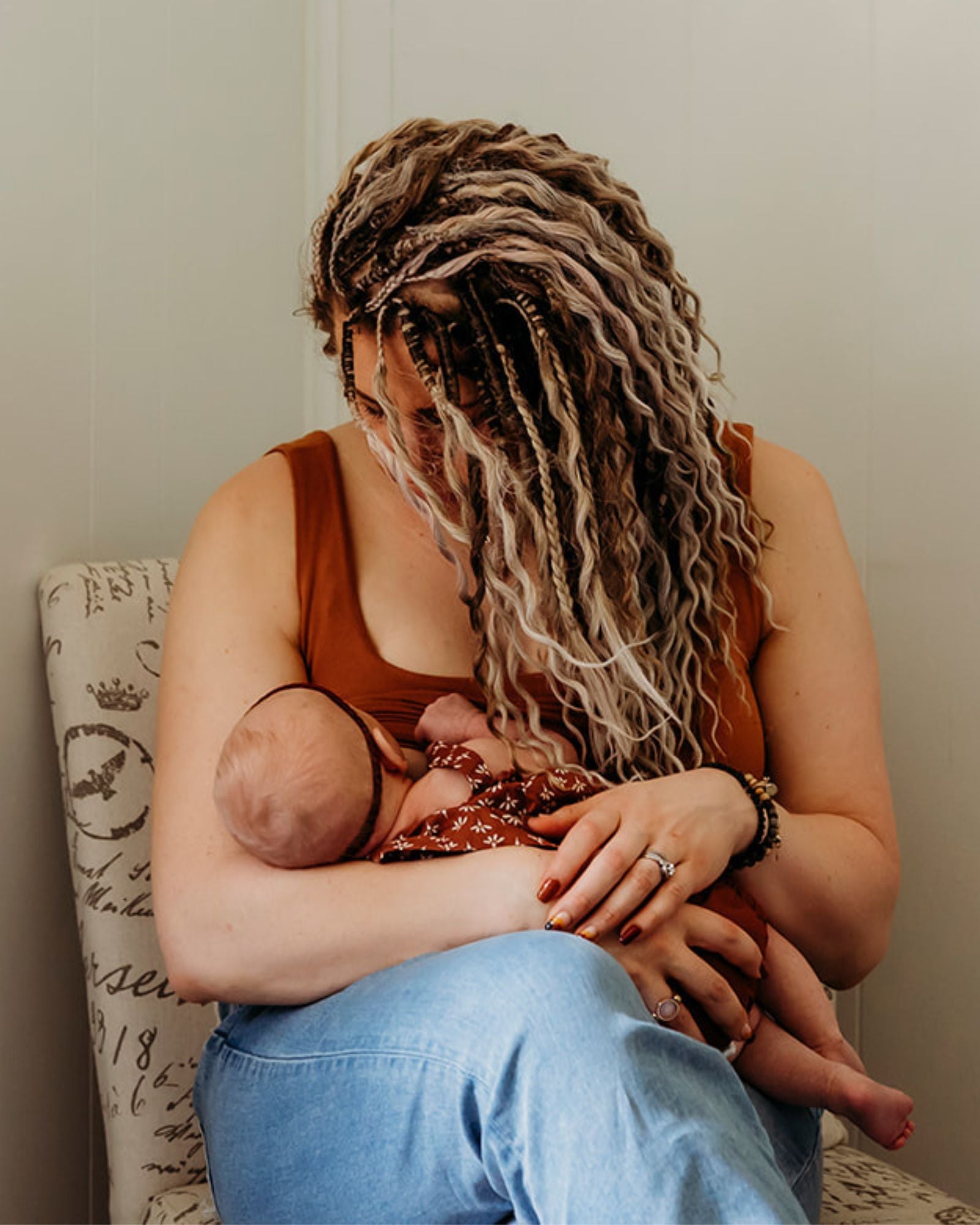 Woman wearing SHORTIES™ Braid-in Hair Extensions breastfeeding a baby in a home setting