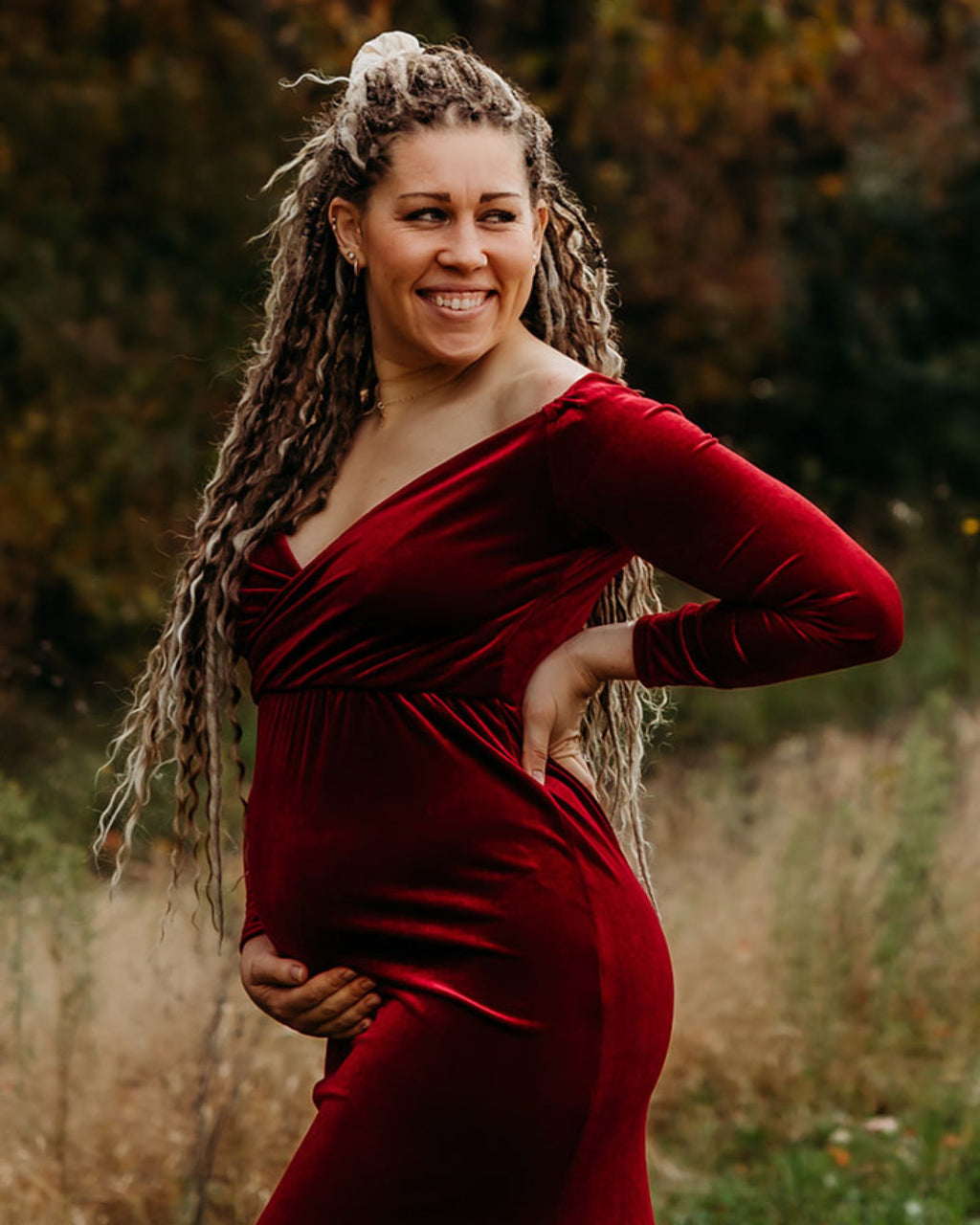 Woman in a red dress standing outdoors with a blurred natural background
