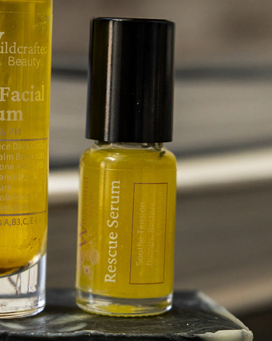 A Rescue Serum roller bottle next to another bottle of amber liquid.