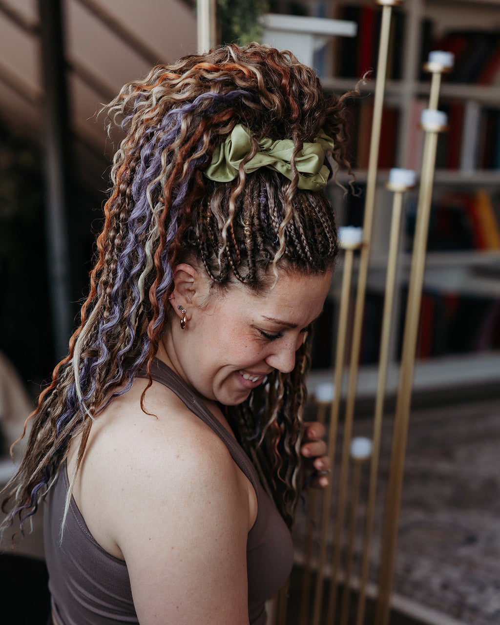 Woman with Venus Long Braid-in Hair Extensions wearing a green flower headband in an indoor setting.