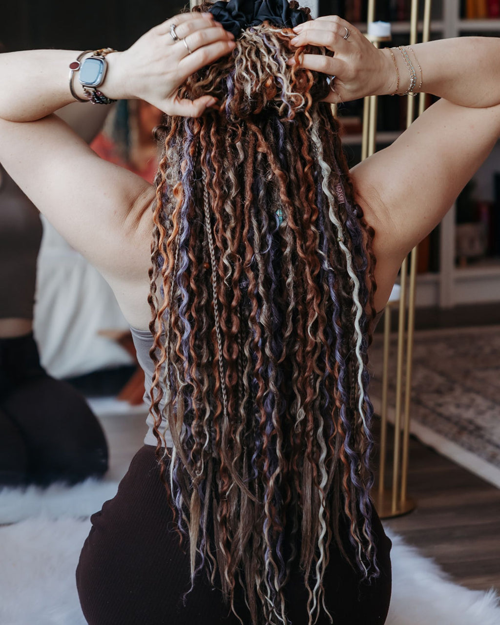 Person holding a bundle of styled Venus Long Braid-in Hair Extensions in a home setting.