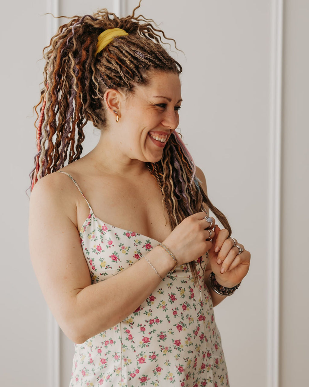 Woman with Venus Long Braid-in Hair Extensions smiling and looking at it against a neutral background