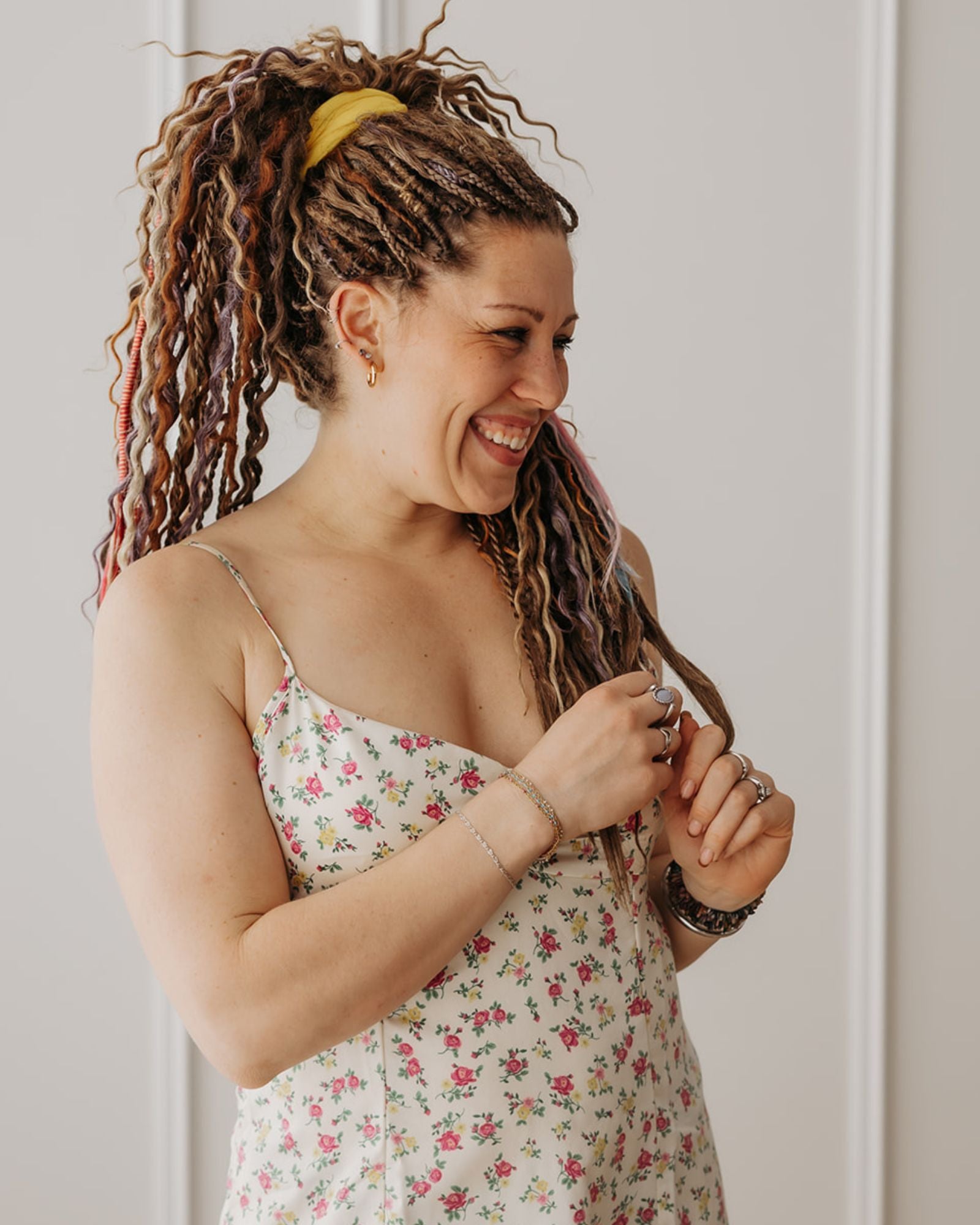 Woman with Venus Long Braid-in Hair Extensions smiling and looking at it against a neutral background