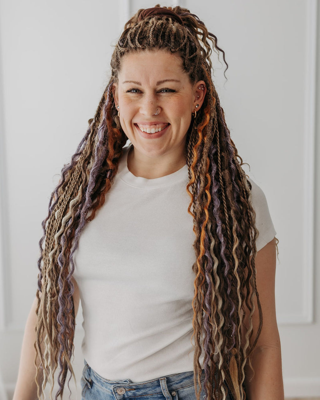 Woman with Venus Long Braid-in Hair Extensions smiling against a white wall
