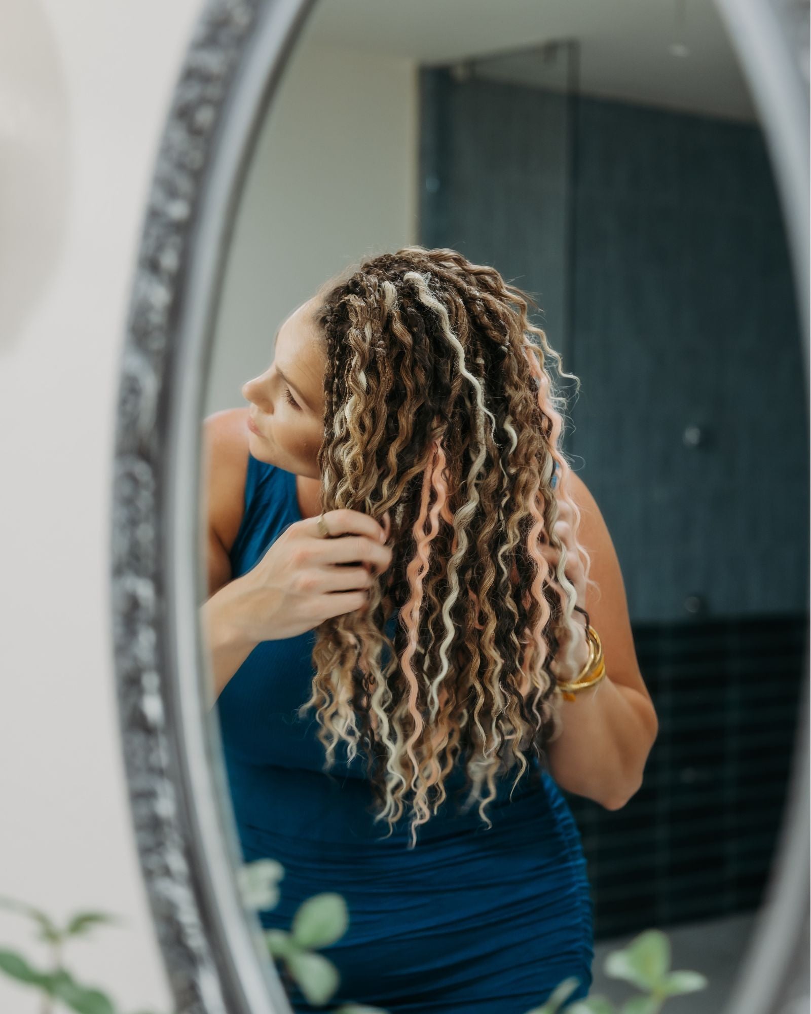 Woman with SHORTIES™ braid-in hair extensions looking at herself in a mirror