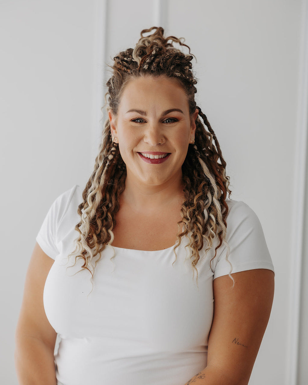 Woman with SHORTIES™ braid-in hair extensions wearing a white shirt against a plain background