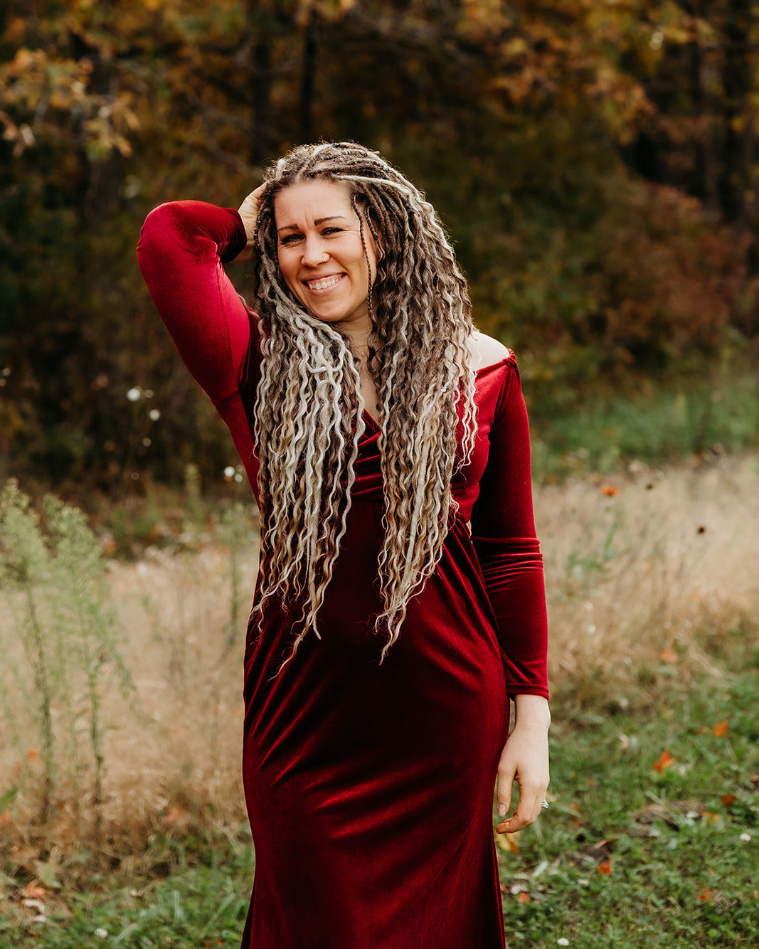 Woman in a red dress with Venus Long Braid-in Hair Extensions standing in a natural setting.