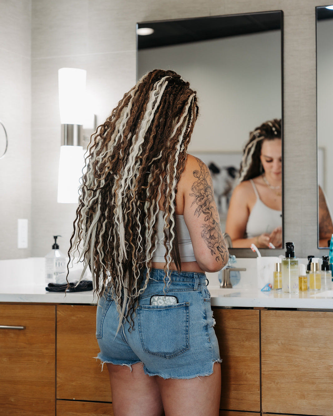Person with Venus Long braid-in Hair extensions standing in a bathroom looking at themselves in the mirror.