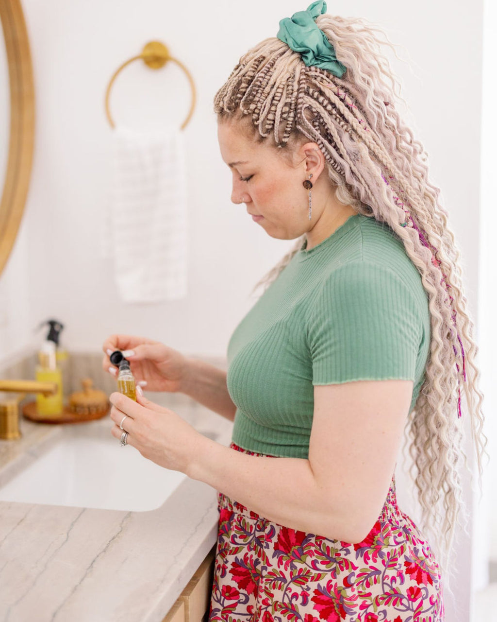 Woman with Venus Long Braid-in Hair Extensions in a kitchen holding a bottle of oil.