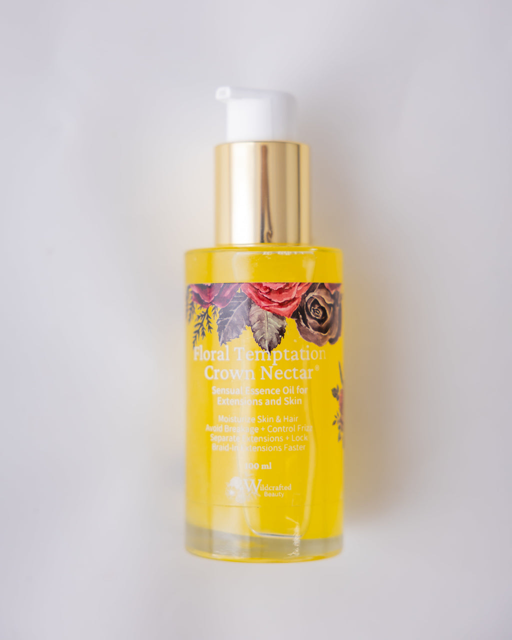 A bottle of Wildcrafted Beauty 'Foral Temptation' Crown Nectar, featuring a gold pump dispenser and a clear bottle filled with yellow oil, set against a plain light gray background.