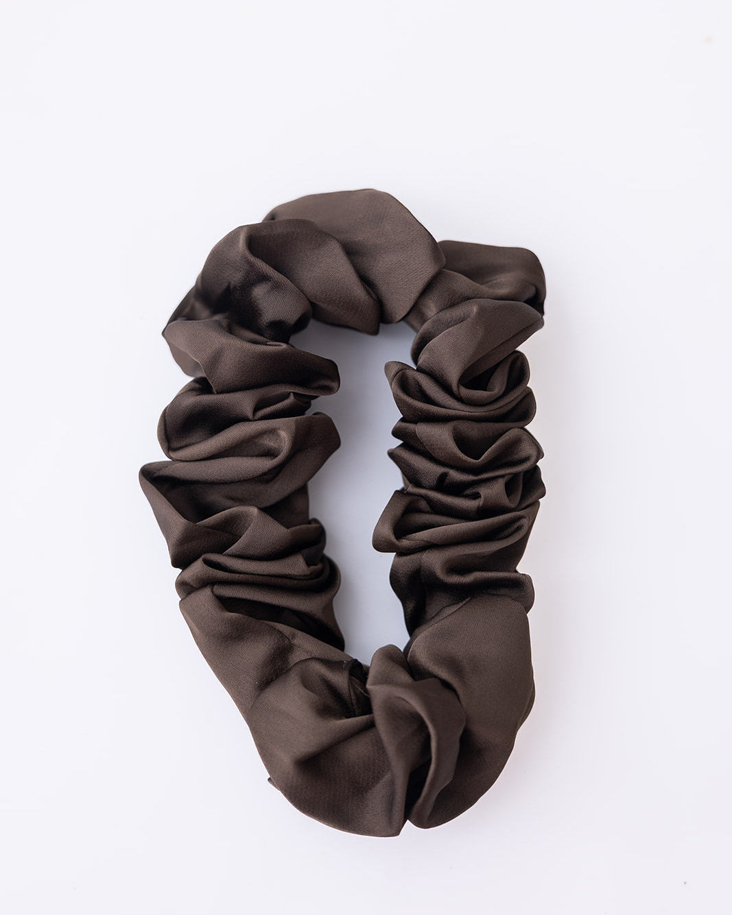 A dark brown satin scrunchie with a gathered, ruffled texture, photographed on a clean white background.