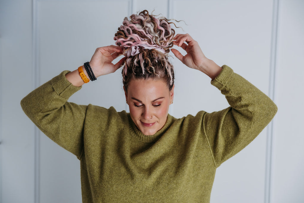 Person adjusting their styled hair against a white paneled wall