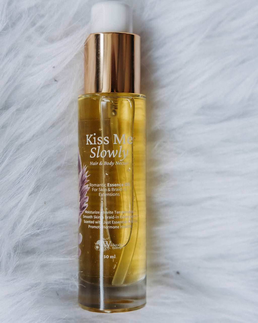 Bottle of 'Kiss Me Slowly' product on a textured white background