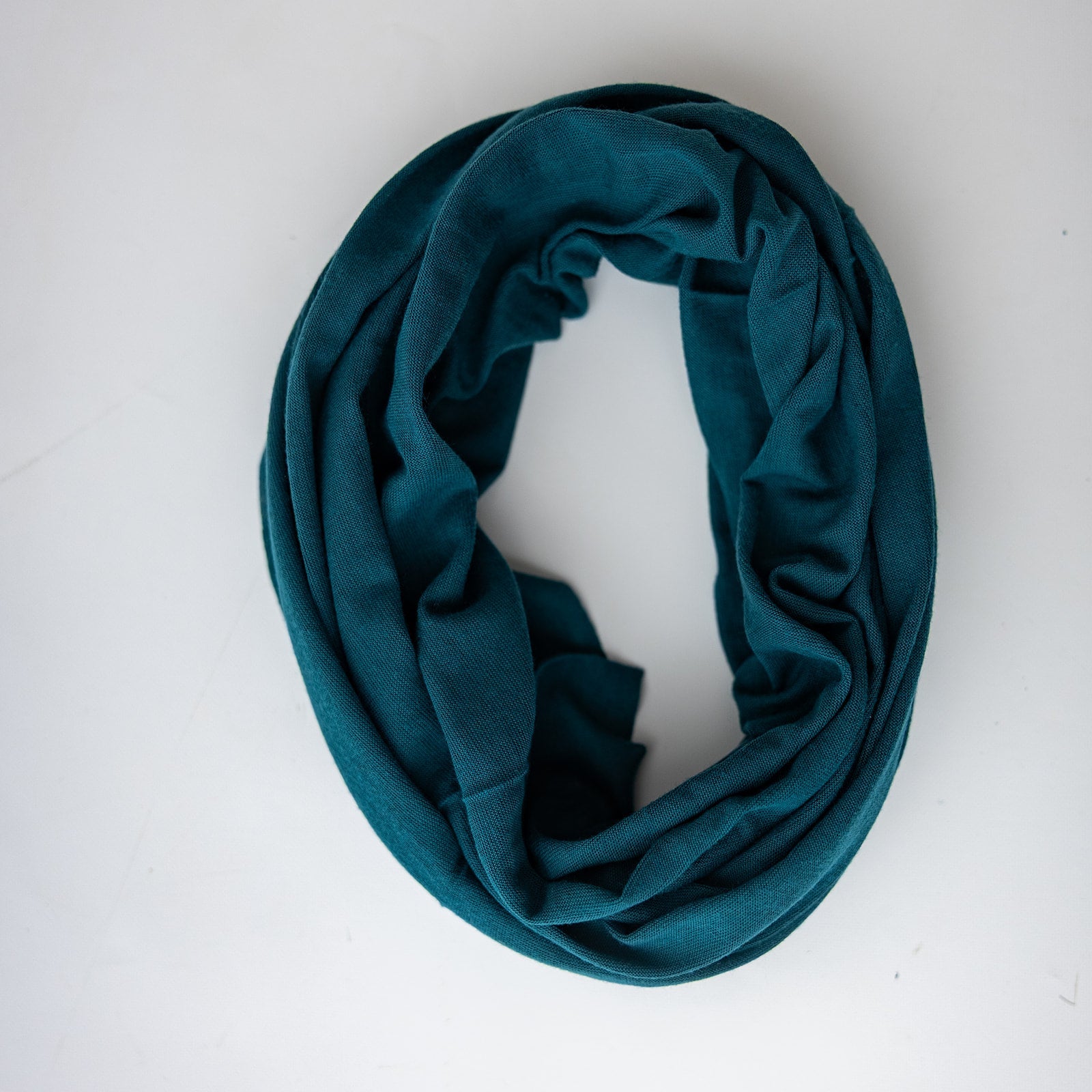 A dark teal Ona Band, draped in a loose circle, displayed on a clean white background.