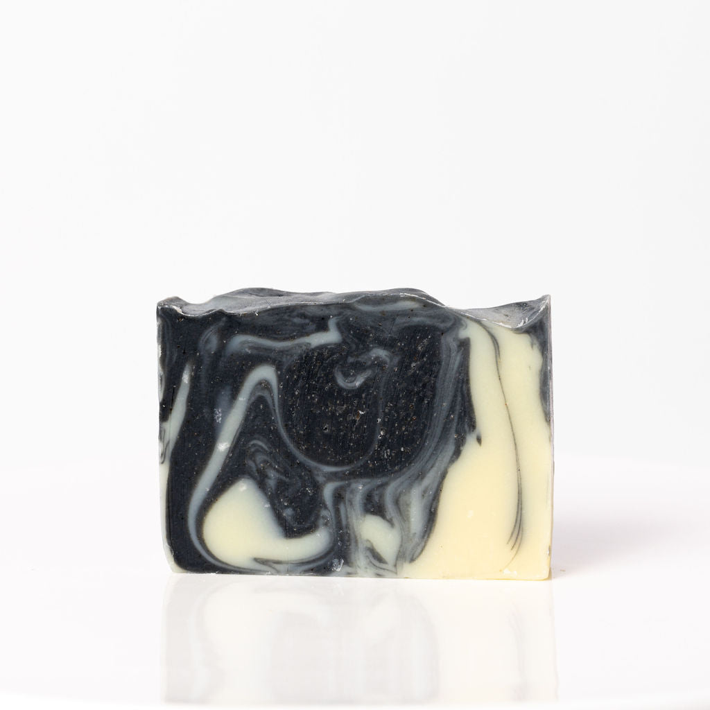 A swirled bar of soap with a combination of light and dark colors, indicating a blend of ingredients, placed against a white background.