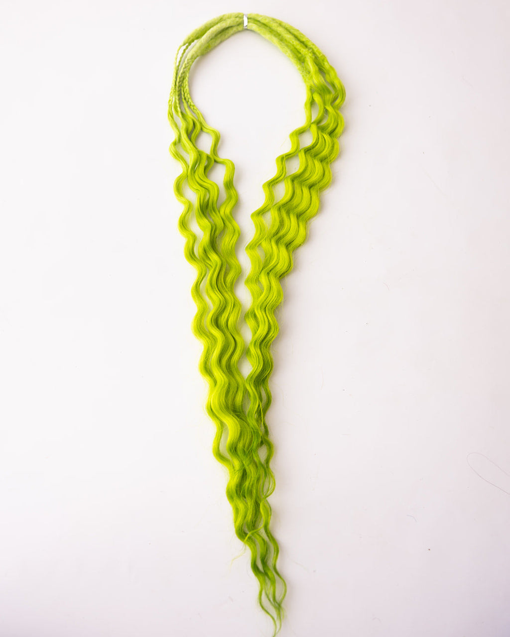 Bright lime green wavy synthetic hair extensions  laid flat on a plain white background.