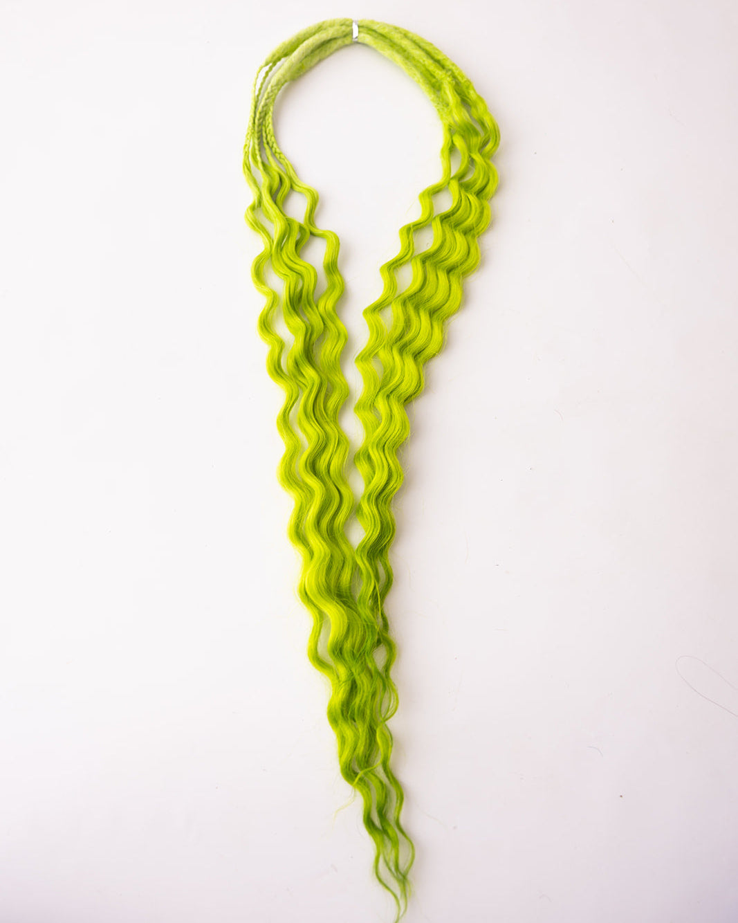 Bright lime green wavy synthetic hair extensions  laid flat on a plain white background.