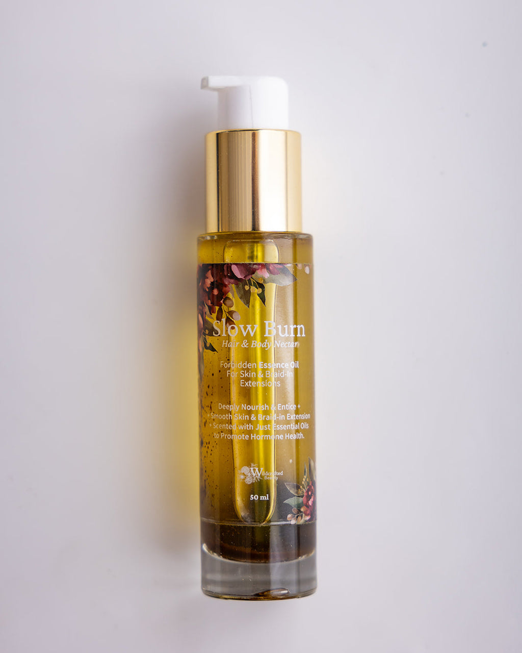 Bottle of Slow Burn body oil with a white pump and gold collar.  Gold oil in a glass bottle against a white background.