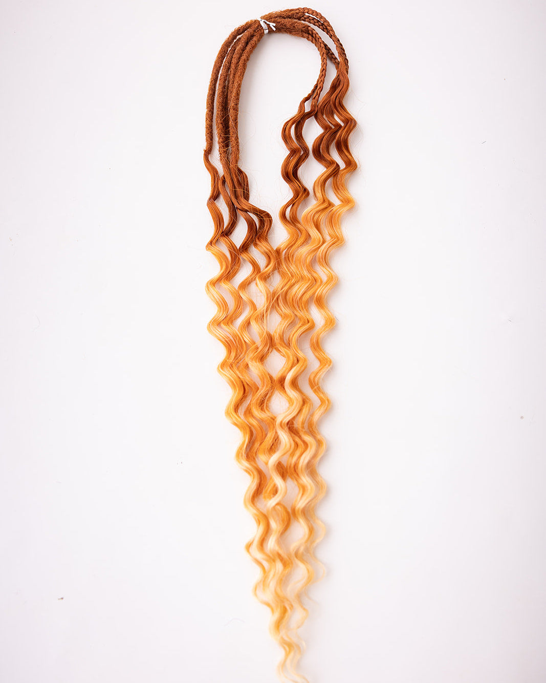 Curly wavy synthetic hair extensions with a rich auburn root ombre transitioning to a warm golden blonde tip, displayed against a plain white background.