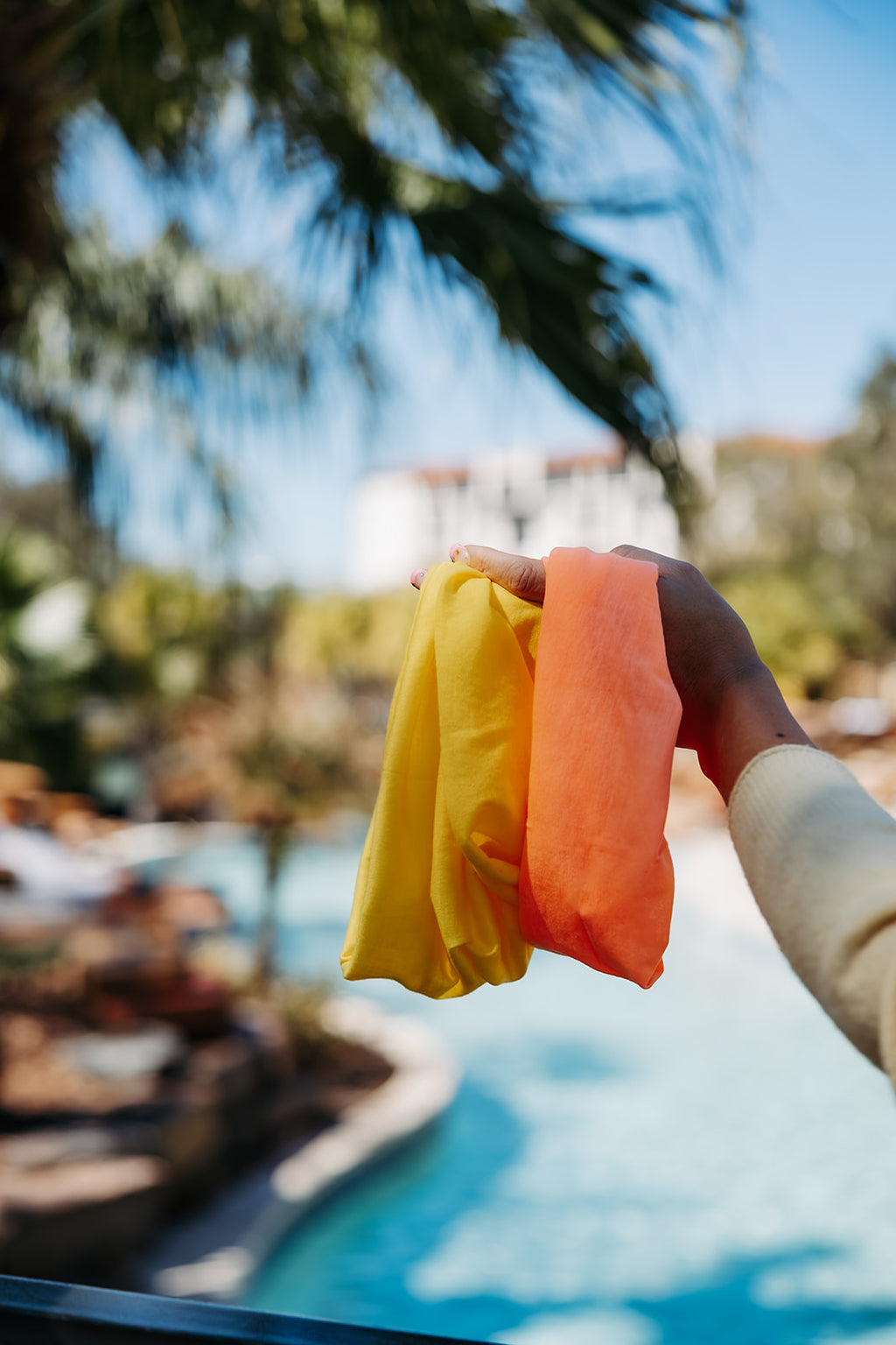 Dandy and Sunrise Ona Bands held in a hand by palm trees