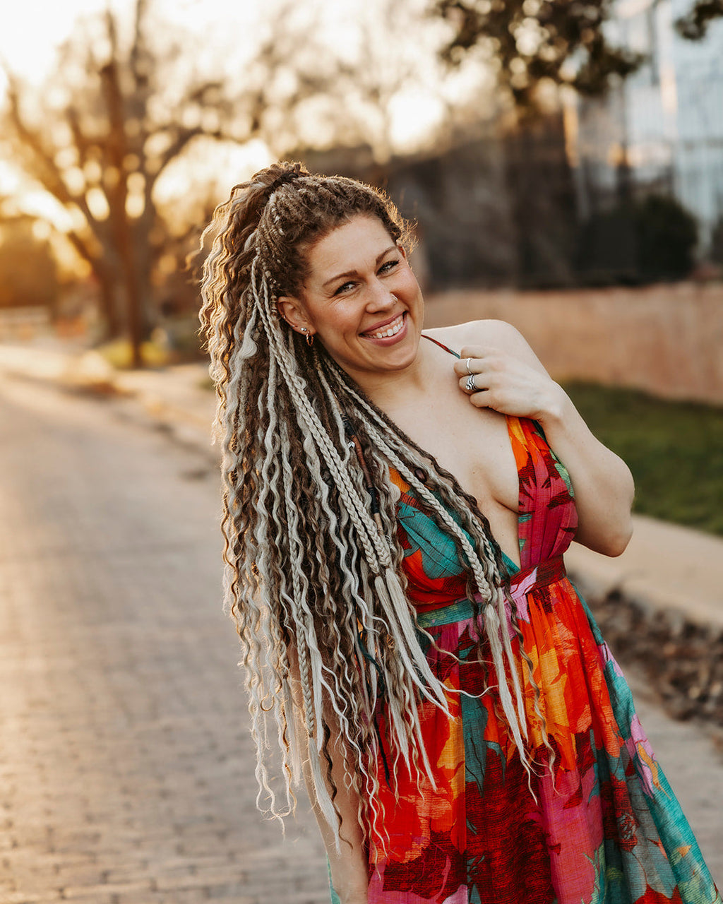 Woman with Venus Long Braid-in Extensions wearing a colorful dress standing outdoors.