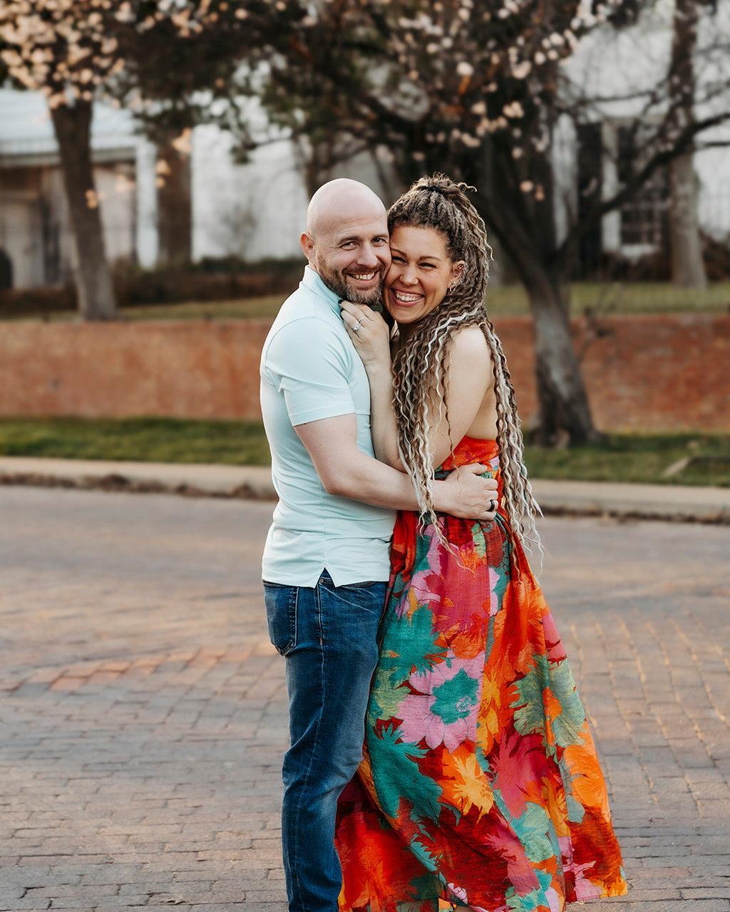 Couple embracing on a street with cherry blossom trees in the background