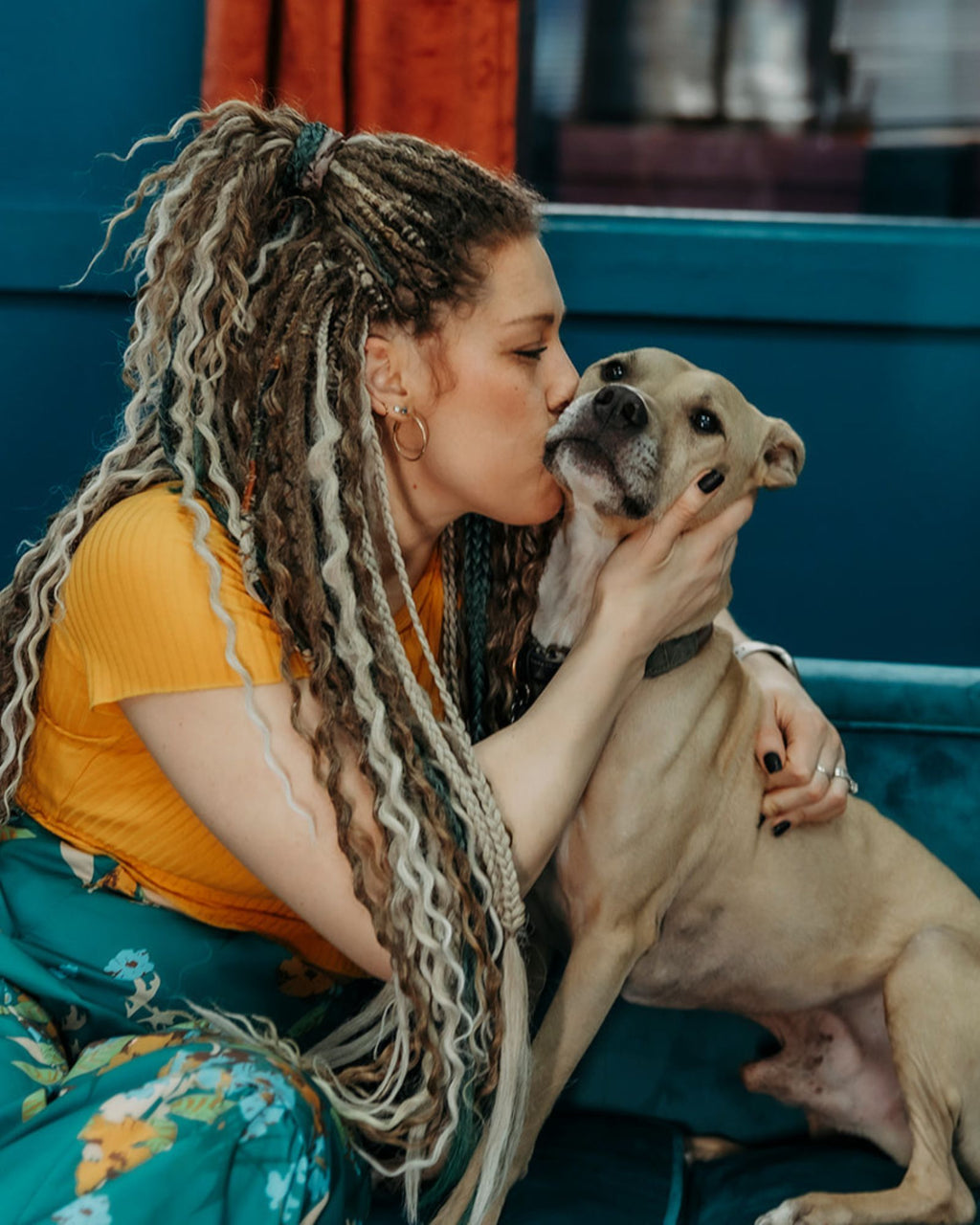 Woman with Venus Long Braid-in Extensions sitting on a couch, petting a dog.