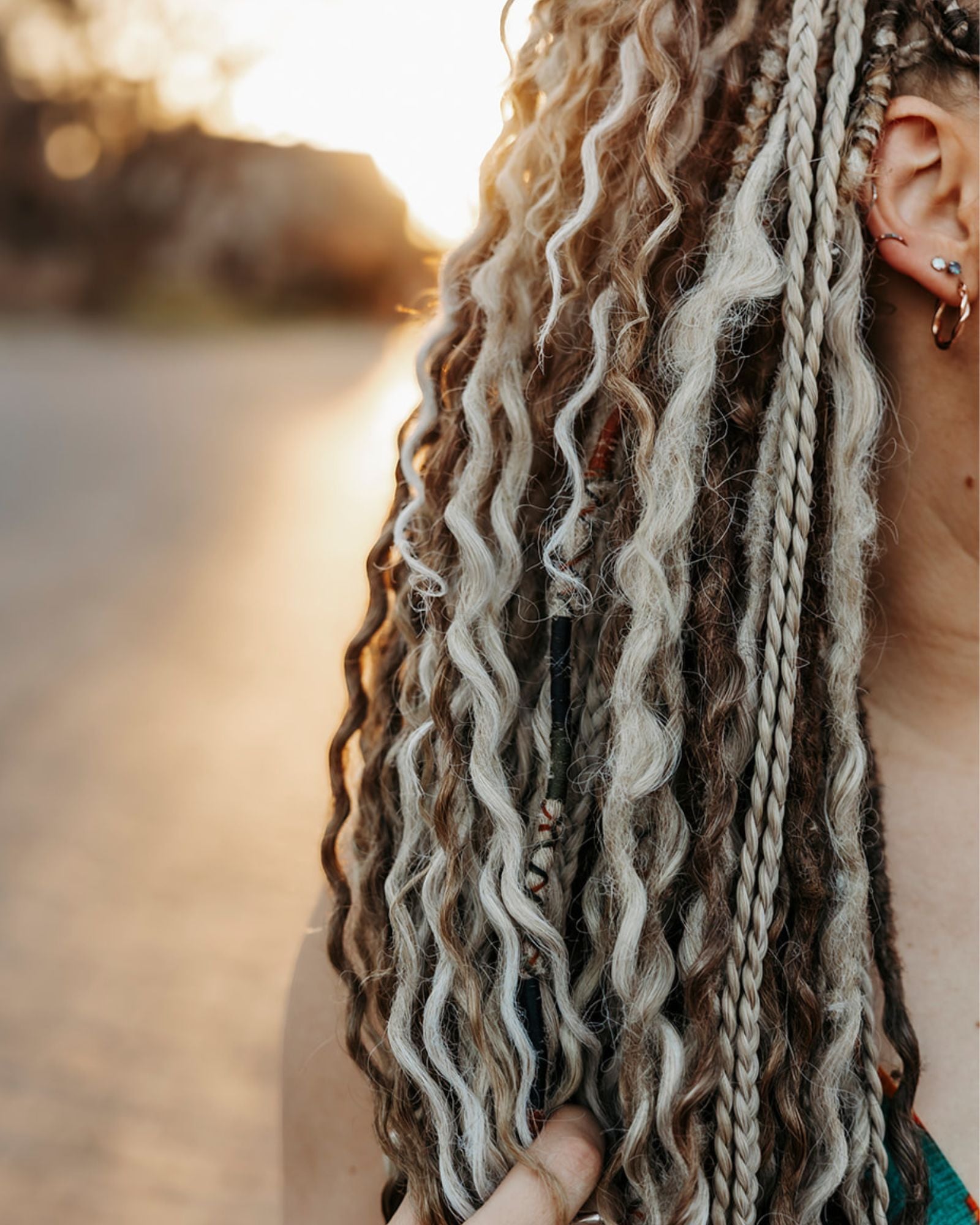 Close-up of a person with Venus Long Braid-in Extensions outdoors during sunset.