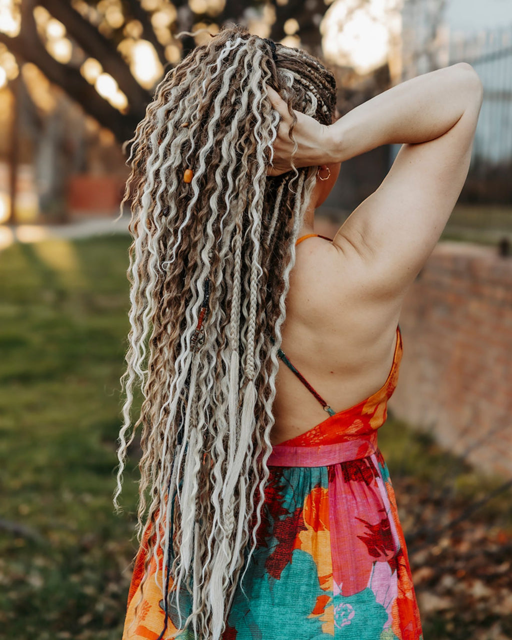 Woman with Venus Long Braid-in Extensions wearing a colorful dress in an outdoor setting.