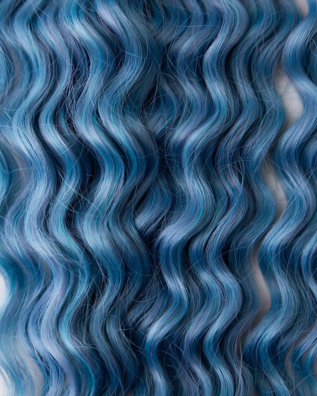 close up of wavy medium blue extensions with blue and purple fibers